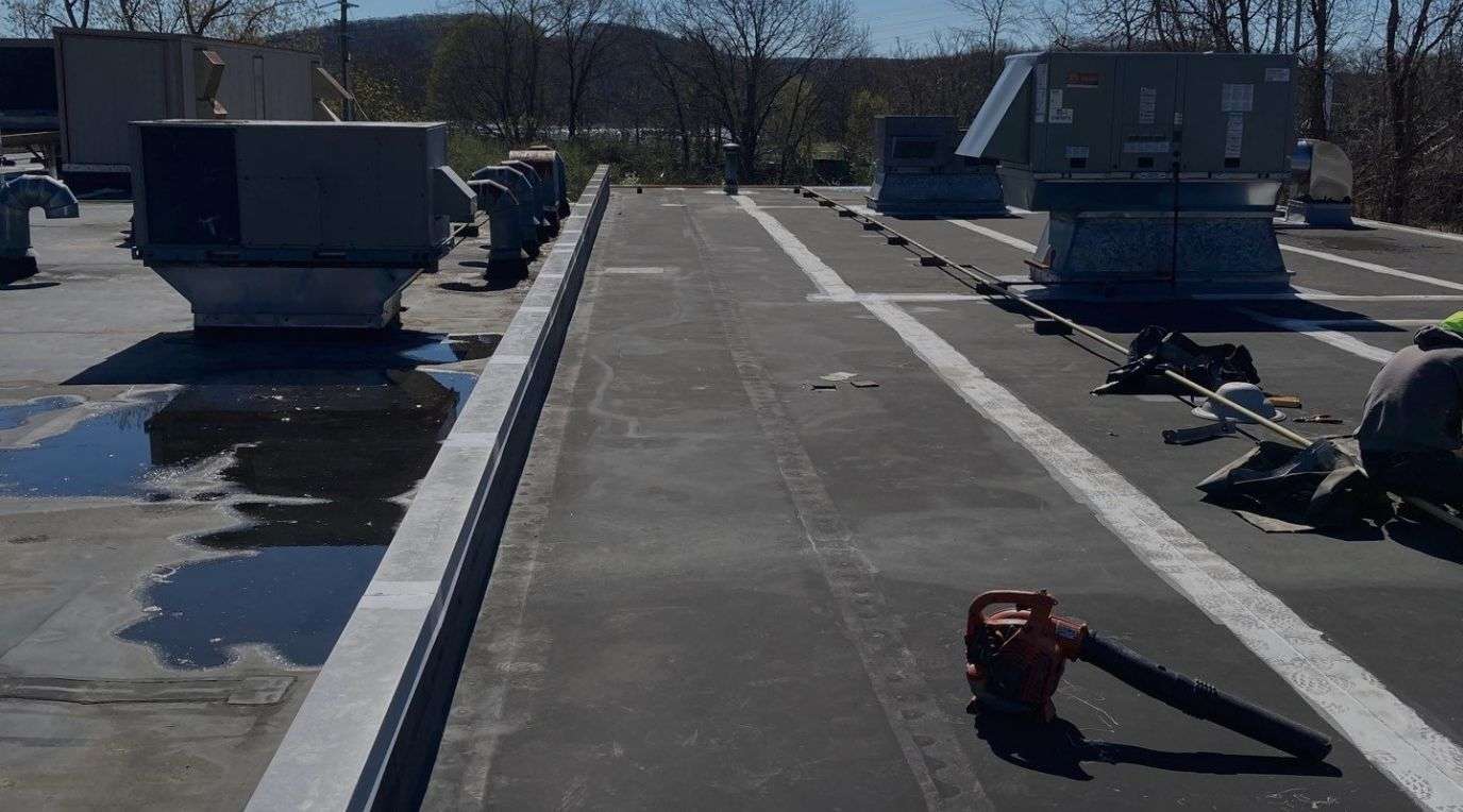 Flat roof surface with visible water pooling on the left side